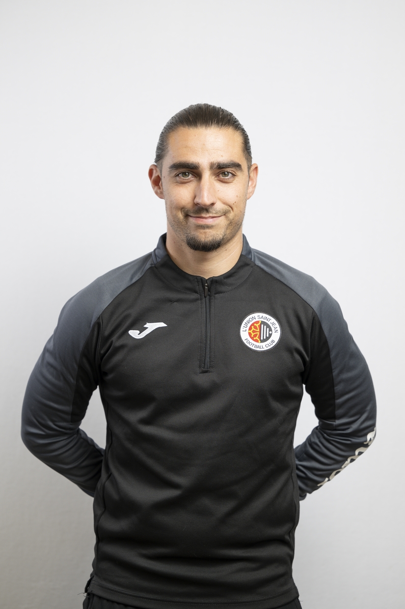 Portrait de J&eacute;r&eacute;my Carenou, membre du staff de L&rsquo;Union Saint-Jean Football Club, en tenue noire sigl&eacute;e Joma avec le logo du club.