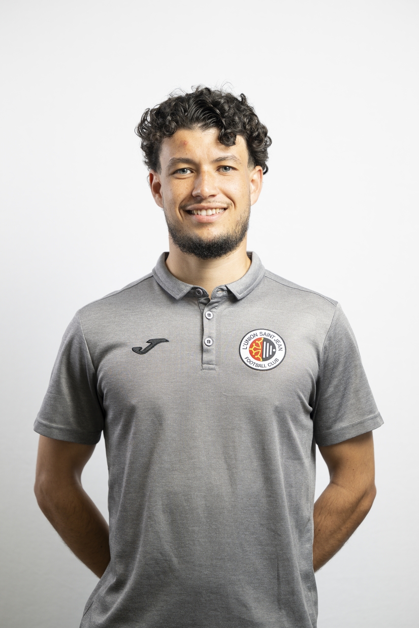 Portrait de Rayan Benarioumlil, membre du staff de L&rsquo;Union Saint-Jean Football Club, en polo gris Joma avec le logo du club, sur fond clair.