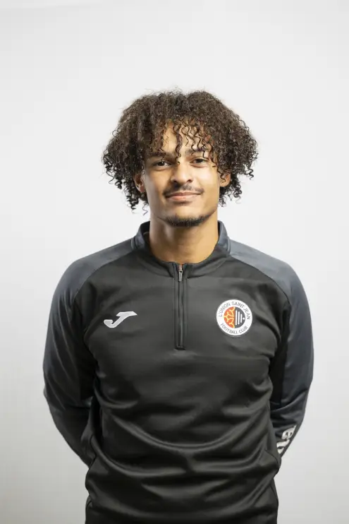 Portrait de Matteo Ribier, membre du staff de L’Union Saint-Jean Football Club, en tenue noire Joma avec le logo du club, sur fond clair.